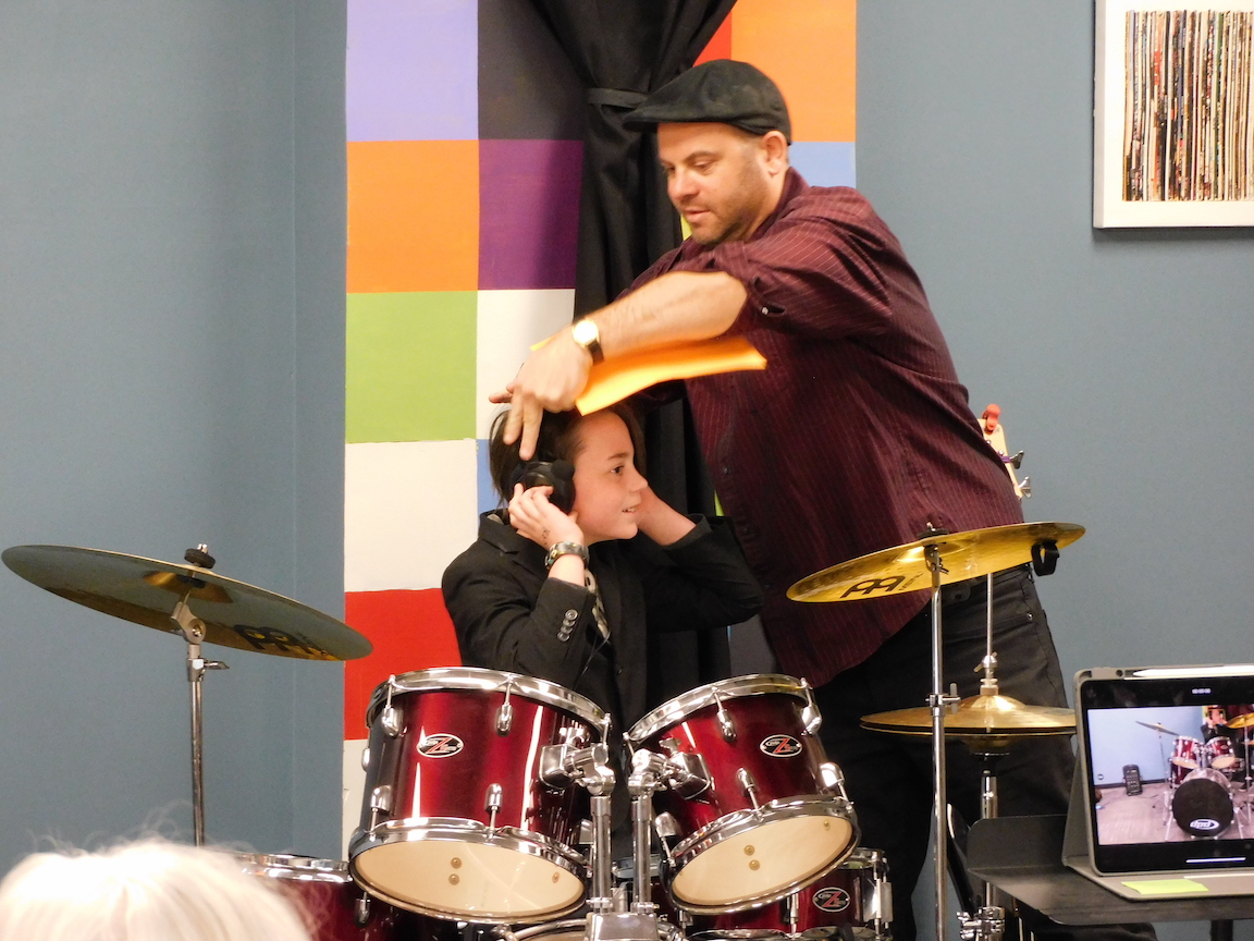 A Child's Song Drum Instructor John Olsson helps student at recital